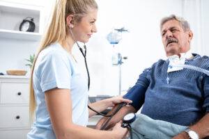 Krankenschwester pflegt einen Patienten, misst Blutdruck und Blutzucker im Krankenhaus
