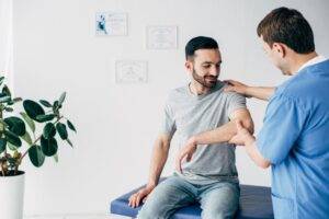 Selektiver Fokus eines Chiropraktikers bei der Untersuchung der Schulter eines Patienten in der Massagekabine einer Klinik