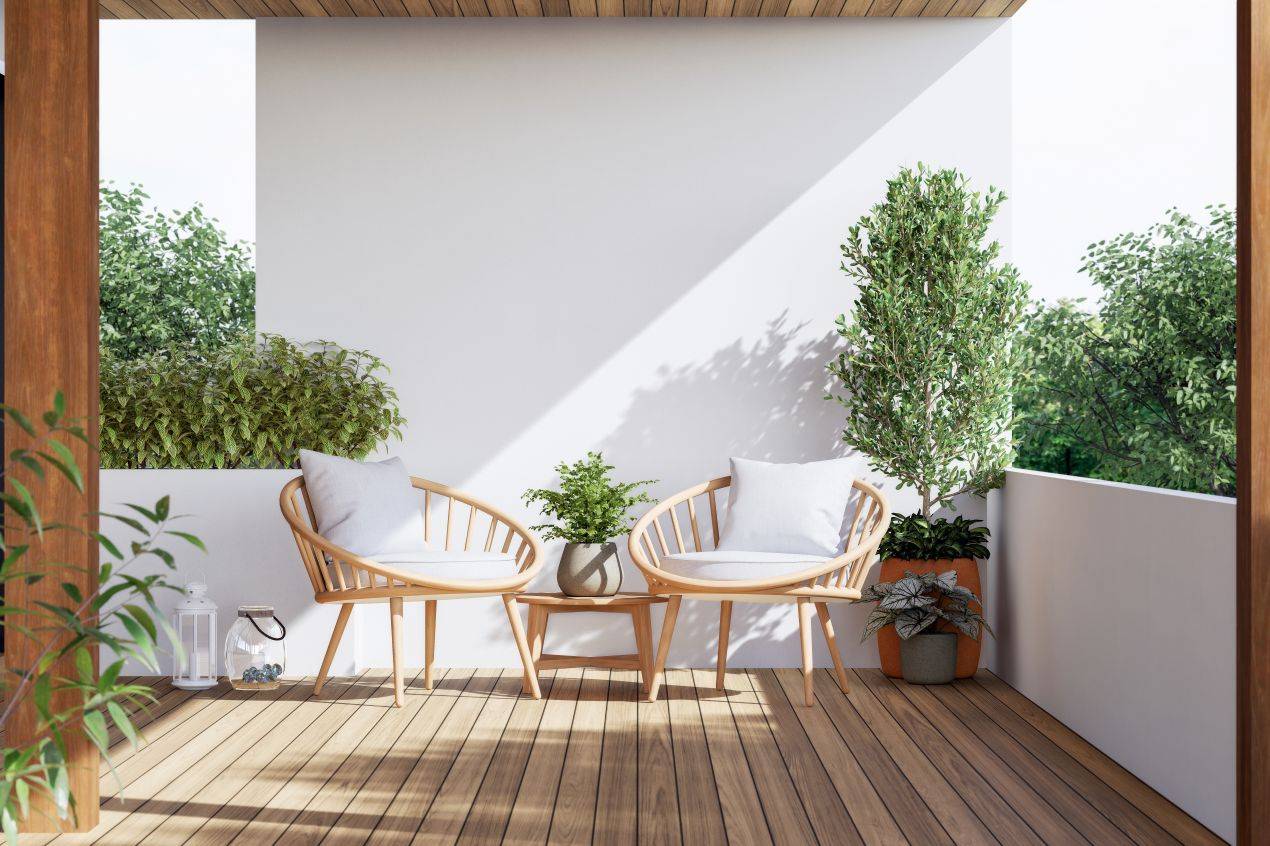 Moderner Balkon mit Holzdeck, zwei Sesseln und dichter Bepflanzung – Beispiel für wohnliche Balkonideen im Gartenbau Wiesloch