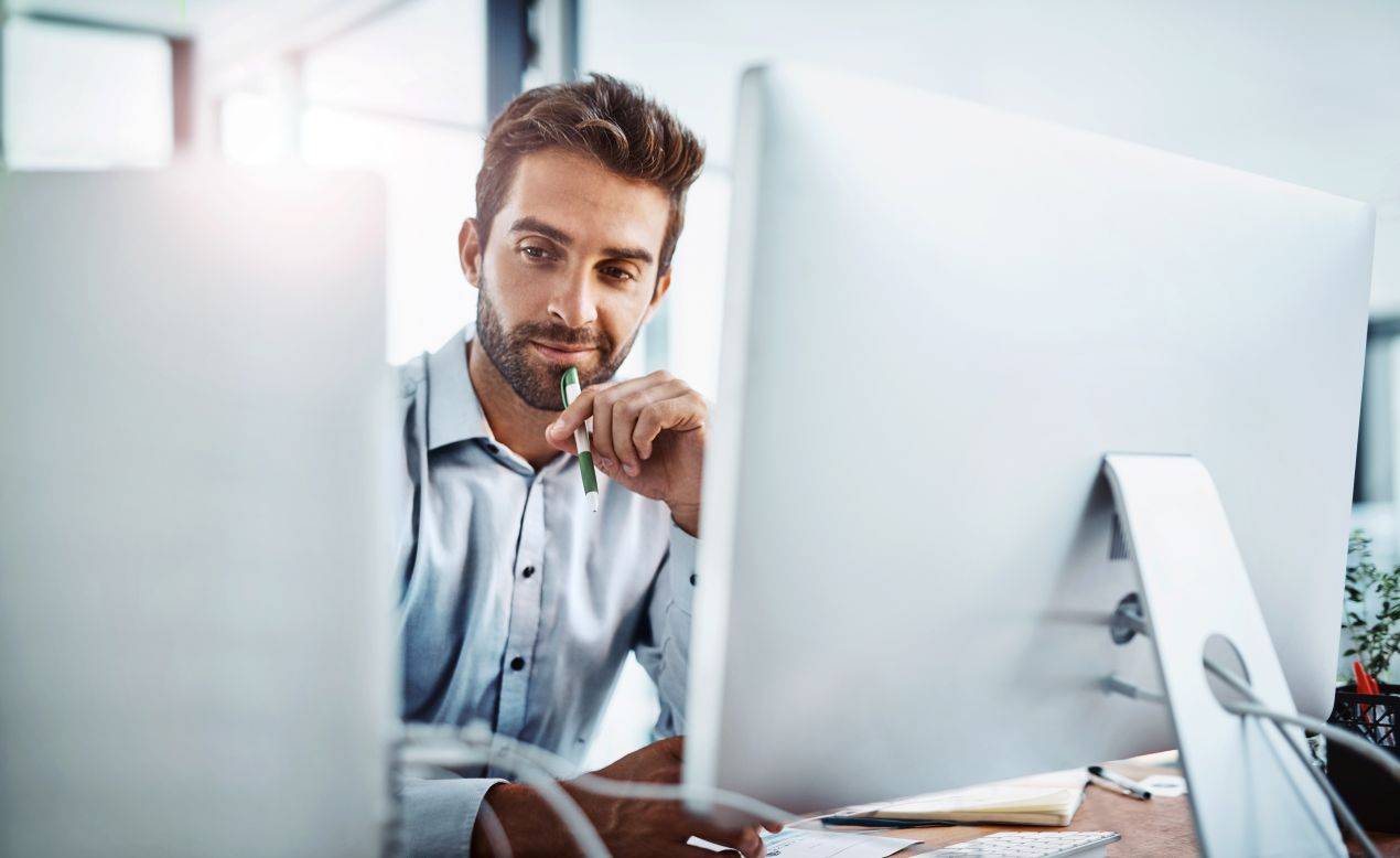 Businessmann vor zwei Monitoren am Arbeitsplatz – Symbolbild fuer Fuehrung und E-Learning Datenschutz