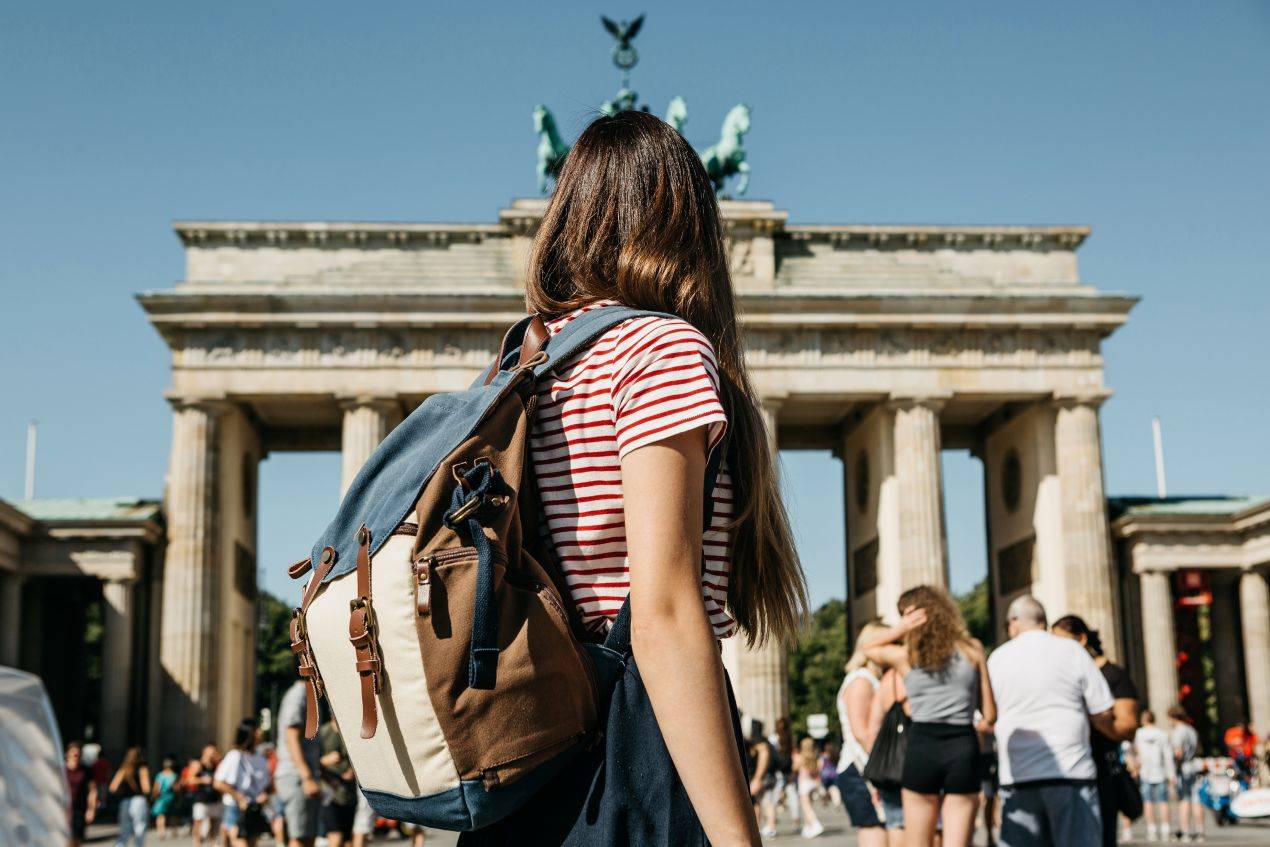 Jugendliche mit Rucksack vor dem Brandenburger Tor während einer Klassenfahrt Berlin