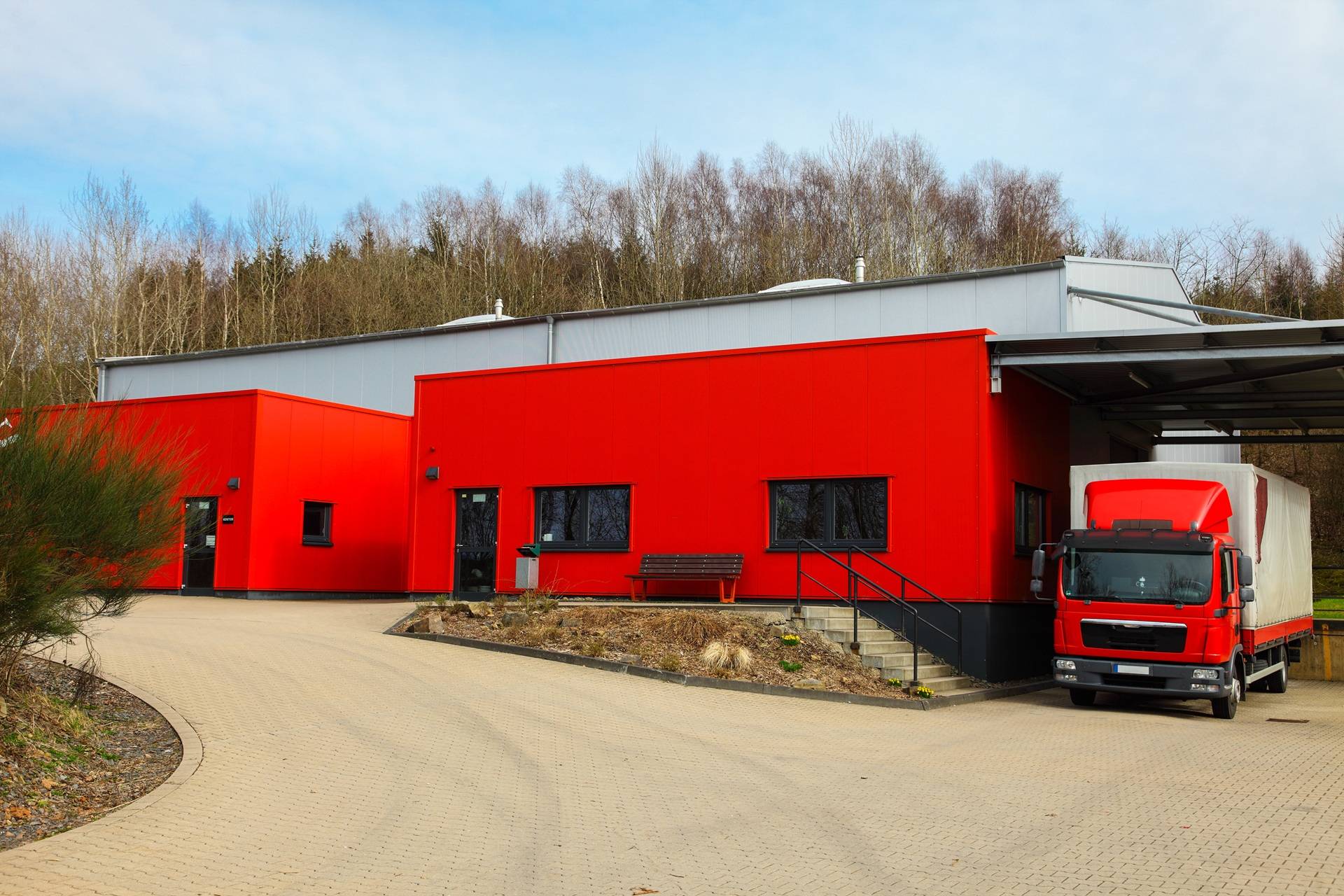 LKW vor roter Logistikhalle | Fahrbahnmarkierung
