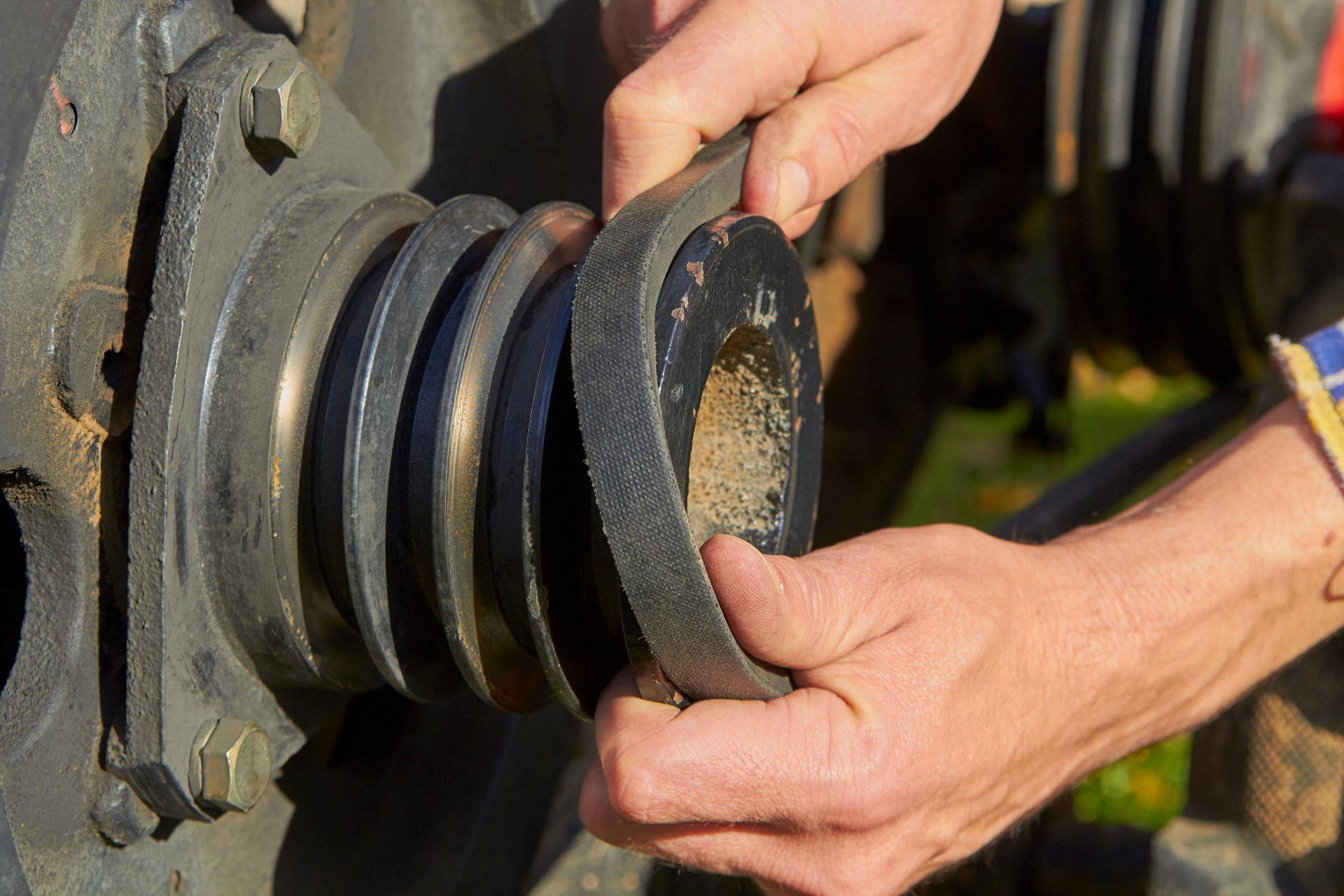 Nahaufnahme eines Mechanikers, der einen Keilriemen auf eine Spannrolle aufzieht – praktischer Einsatz im Maschinenbau